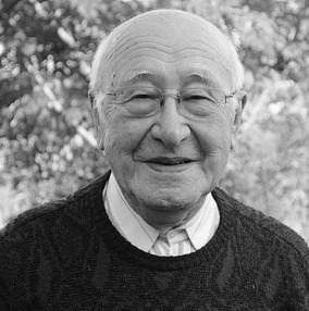 Black and white photo of older white male with glasses, smiling